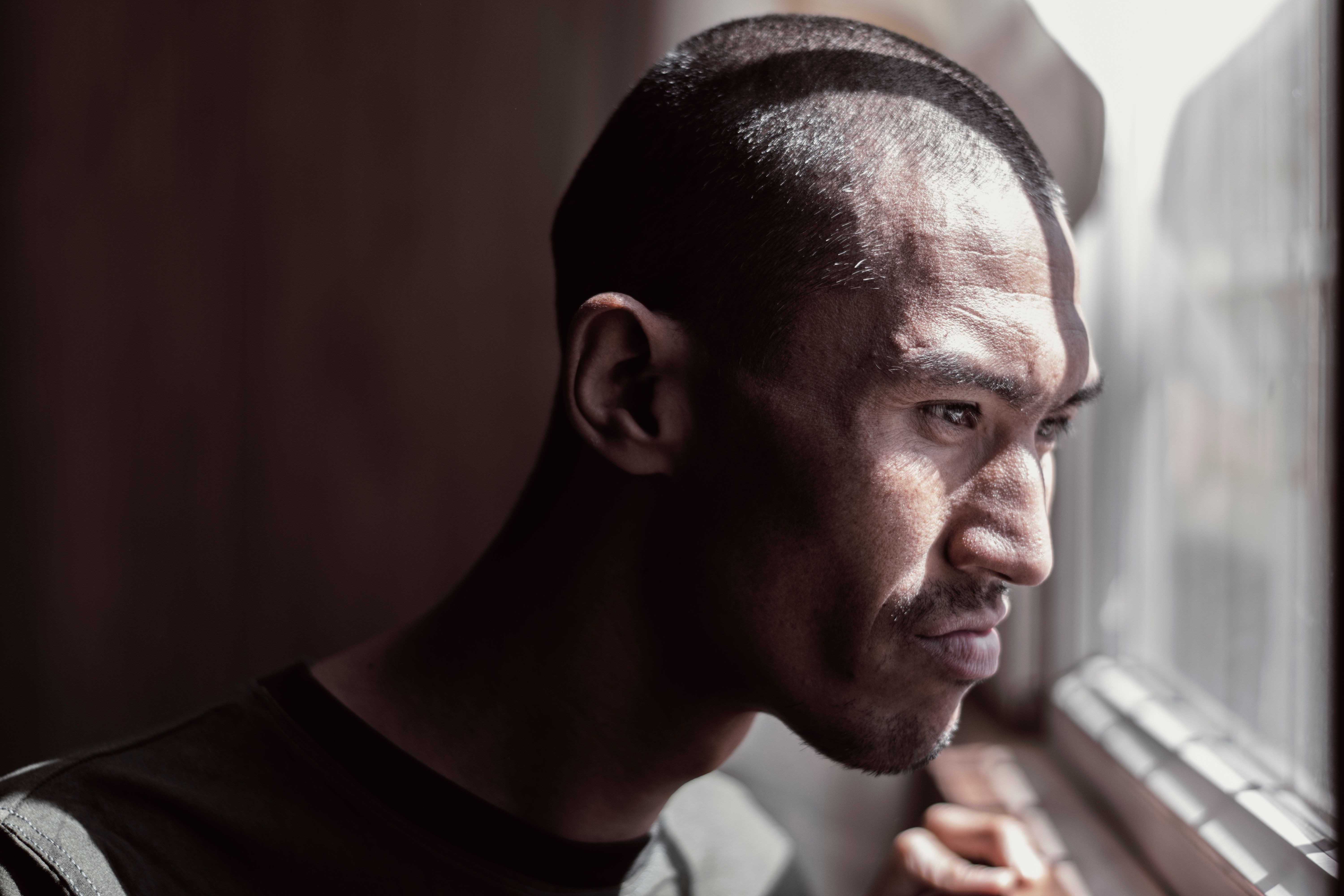 Portrait of a contemplative man looking out the window, bathed in natural light.