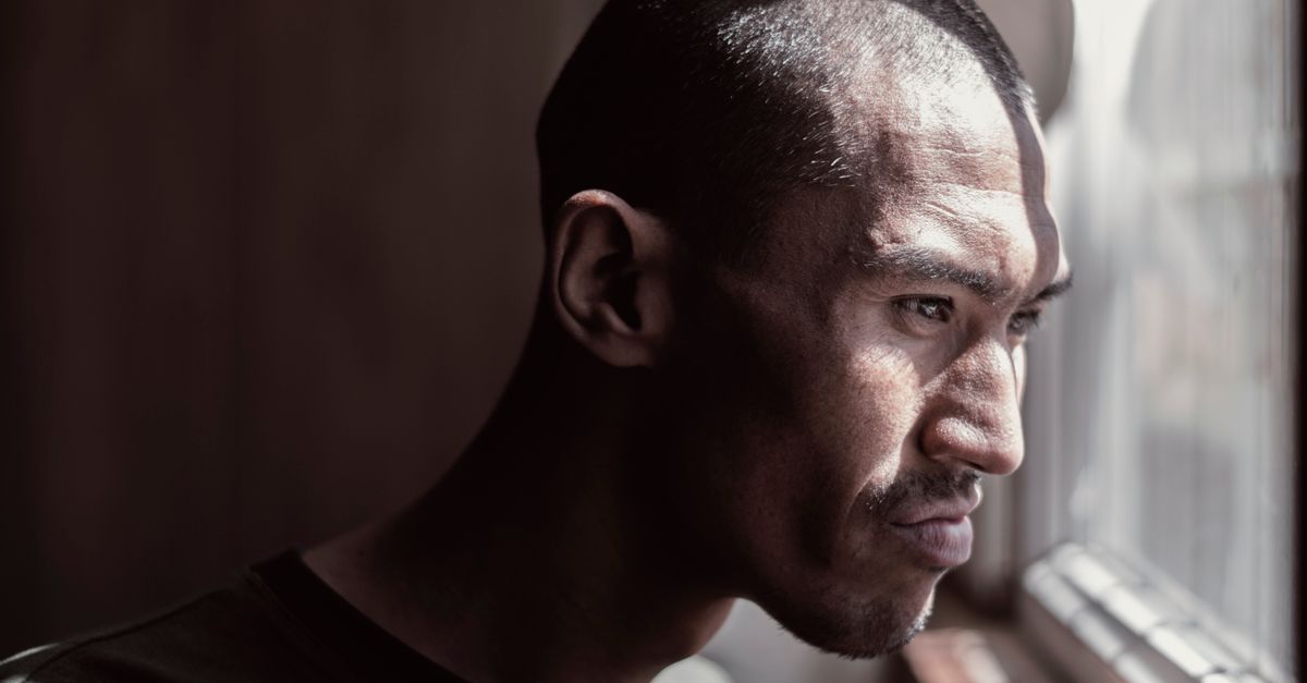 Portrait of a contemplative man looking out the window, bathed in natural light.