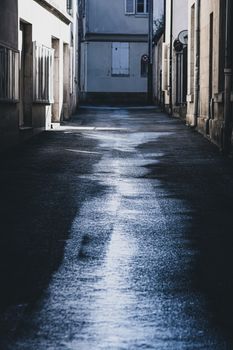 Wet urban alley reflecting light, creating a moody atmosphere post-rain.
