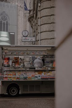 A food truck on a cobblestone street near historic buildings in daylight.