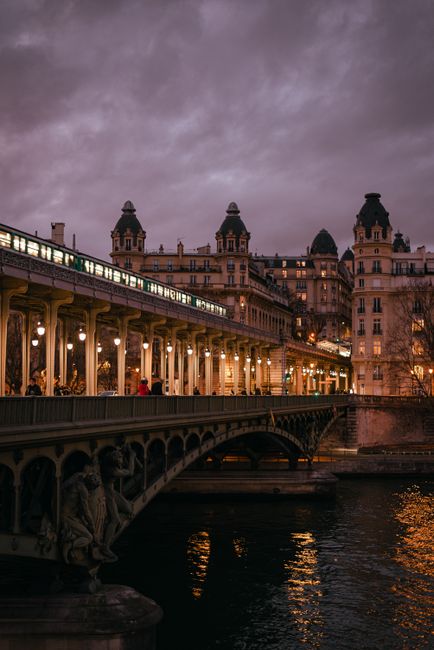 Stunning view of a Parisian bridge and classic architecture at dusk over the Seine River.