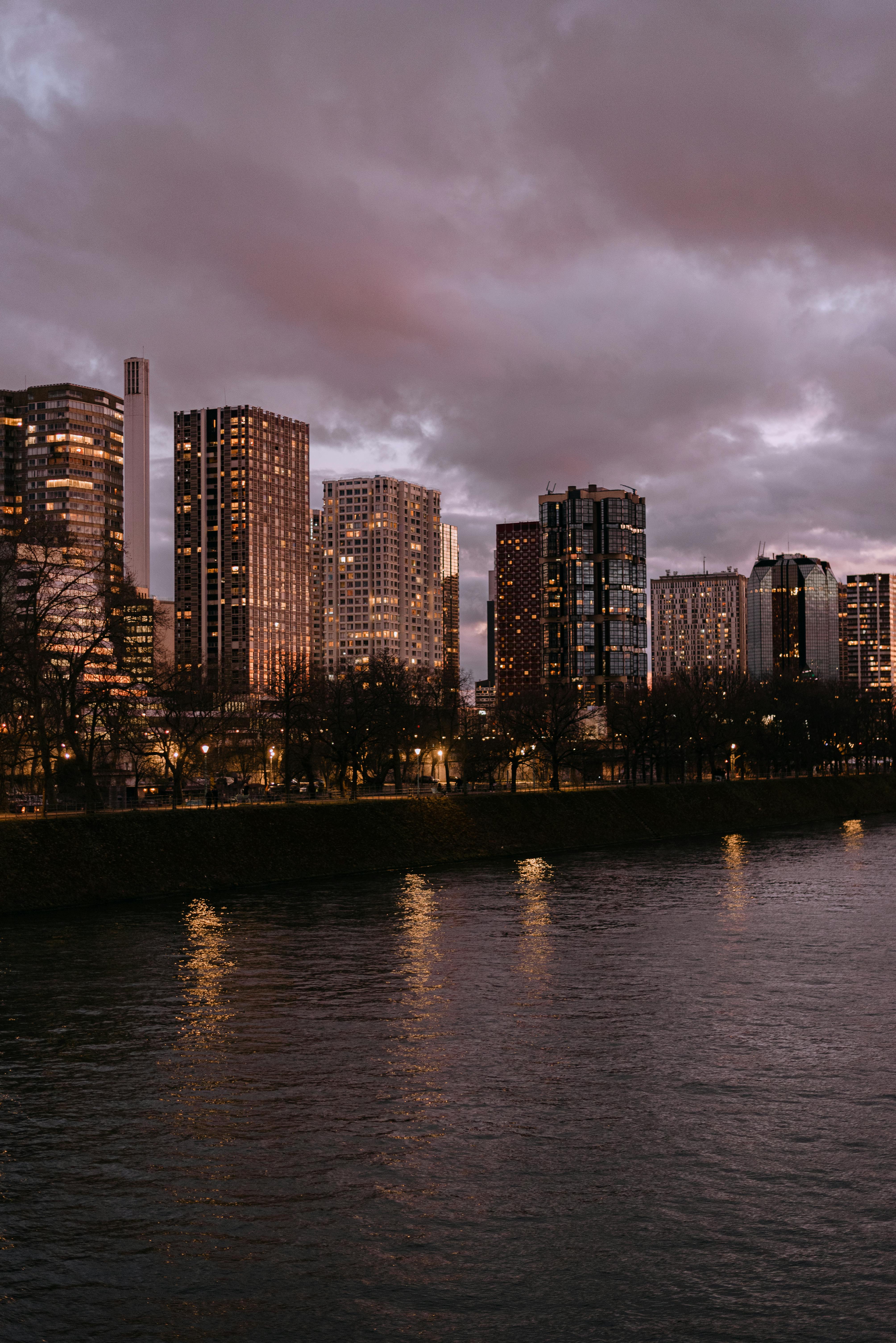 Panoramic view of Parisian skyscrapers reflecting on the Seine at dusk.