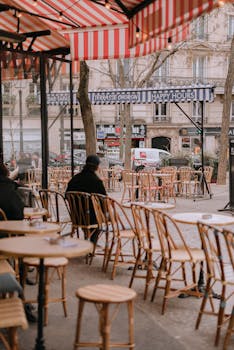 Elegant Parisian terrace with wicker chairs and striped awning. Ideal for travel and lifestyle imagery.