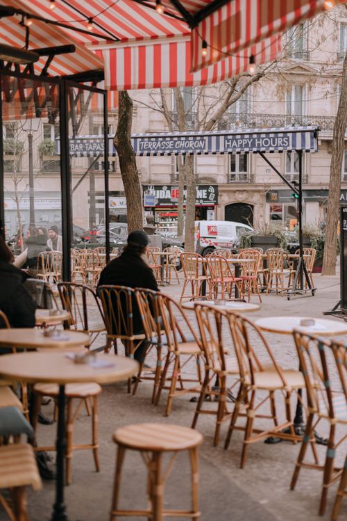 Free Elegant Parisian terrace with wicker chairs and striped awning. Ideal for travel and lifestyle imagery. Stock Photo
