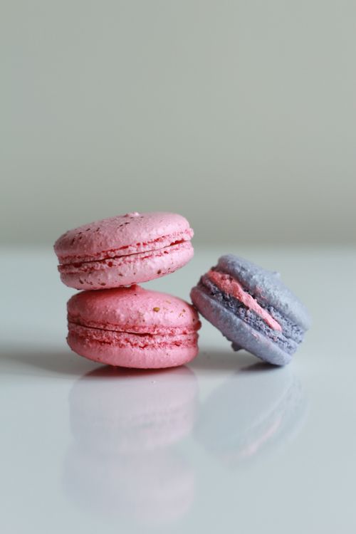 Free Close-up of vibrant pink and blue macarons stacked on a reflective white surface. Stock Photo