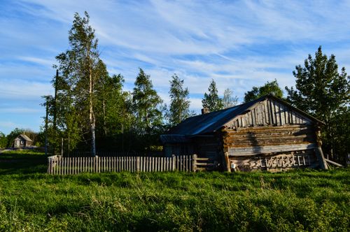 Free A picturesque rustic wooden cabin in the rural Russian countryside, surrounded by lush greenery and clear skies. Stock Photo