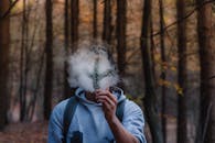 秋天的森林里，一名男子手持松枝，立于烟雾之中