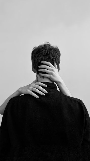 Black and white photograph of a couple embracing, showing a woman's hand on a man's neck.
