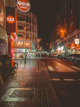 Bustling street in Dubai at night with bright neon lights and urban atmosphere.