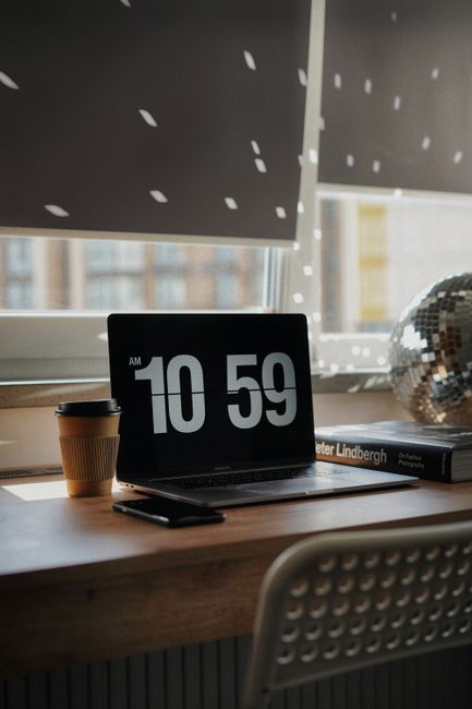 Cozy home office setup with a laptop, coffee, and disco ball by a window in Kyiv.