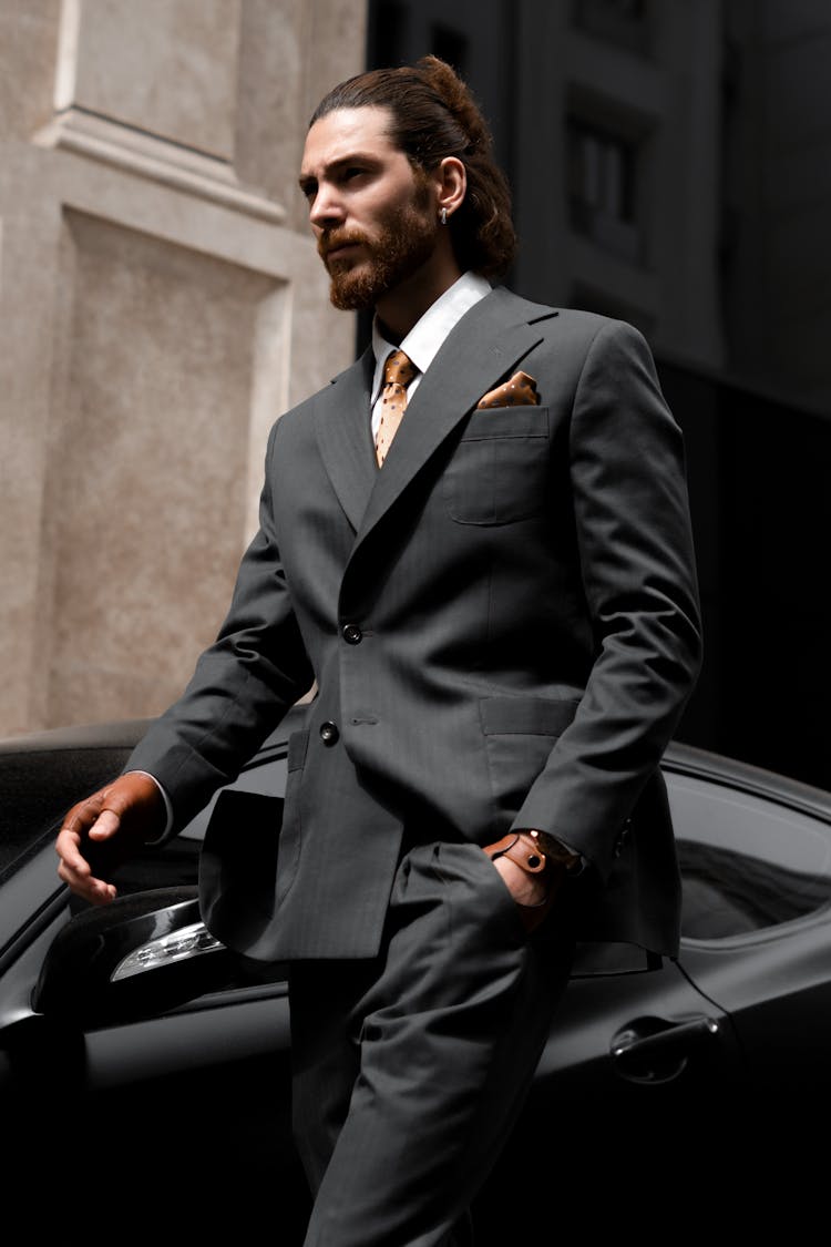 Elegant Man In A Suit Walking By A Sports Car