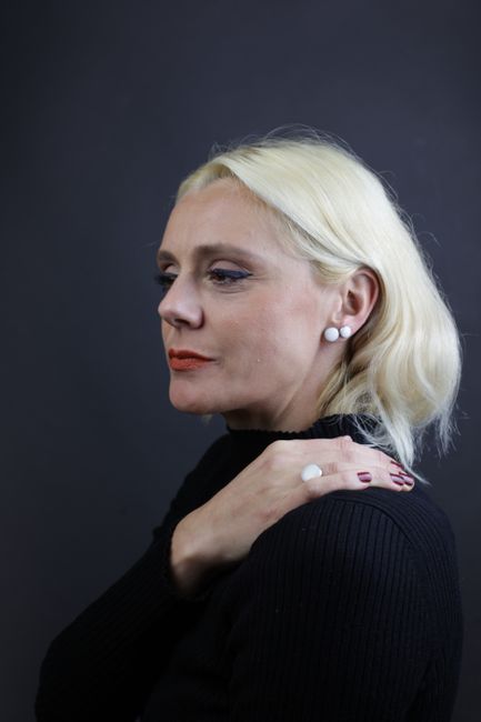 Stylish portrait of a blonde woman in a black outfit with red nails, exuding elegance and confidence.