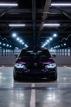 A sleek sports car photographed in a dimly lit urban parking garage.
