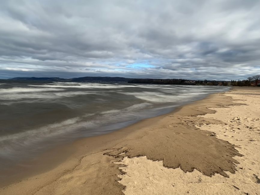 Calm beach scene with gentle waves under a cloudy sky, offering a serene coastal view.