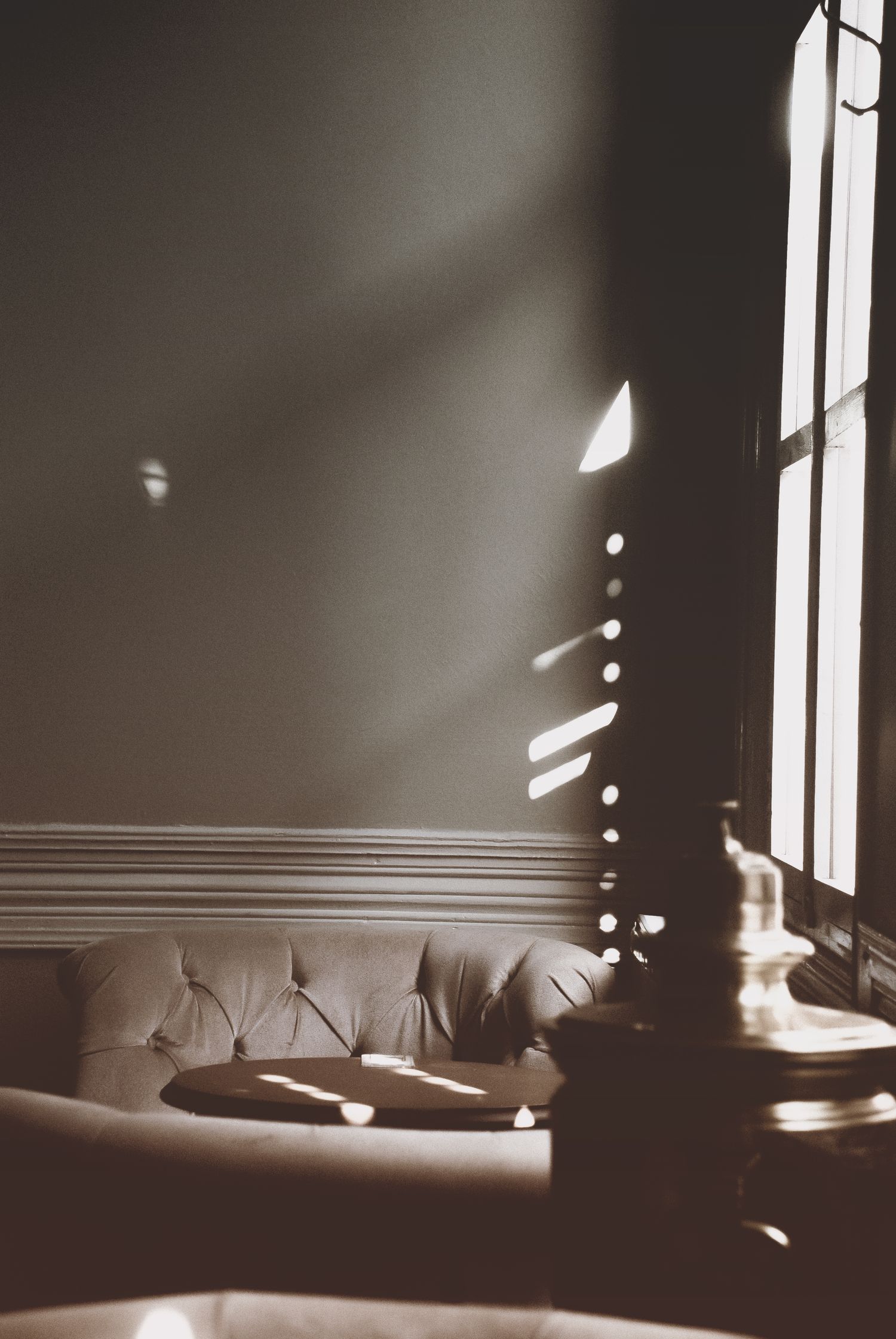 Window light falling across an empty upholstered seat and a pale wall