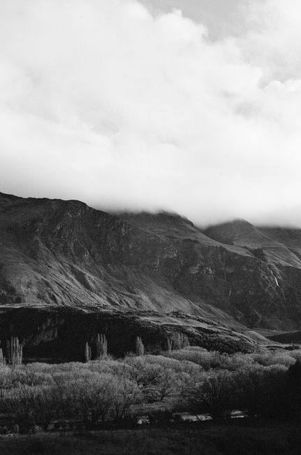 Captivating black and white image of fog enveloping a rugged mountain range.