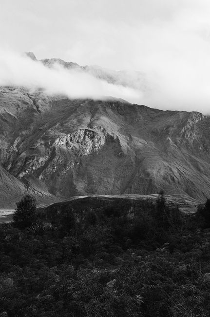 Captivating black and white photo of mountain range shrouded in fog, offering a tranquil view.