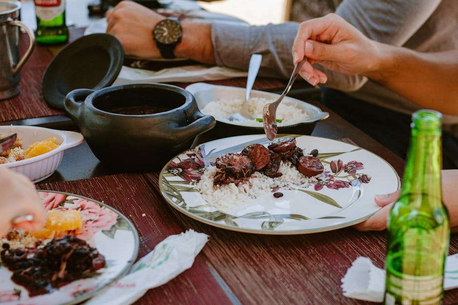 Close-up of authentic Brazilian feijoada served on a table with rice, oranges, and beverages.