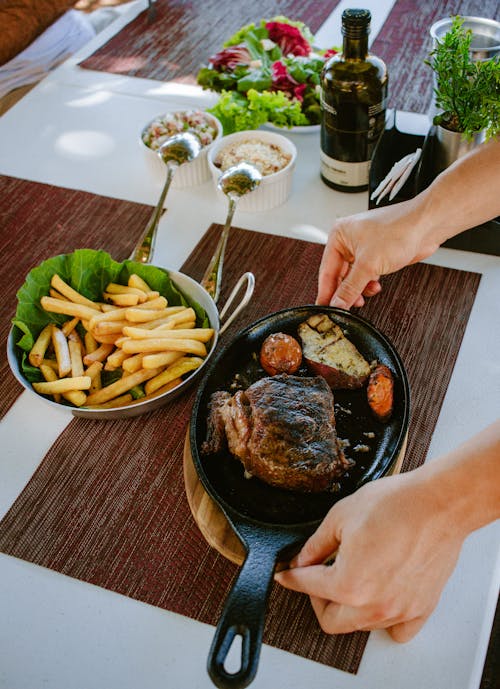 Woman Putting a Meat Dish on a Table 