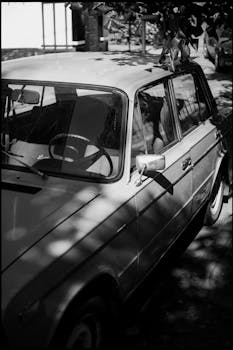 Classic car on a city street in black and white, showcasing retro charm and urban atmosphere.
