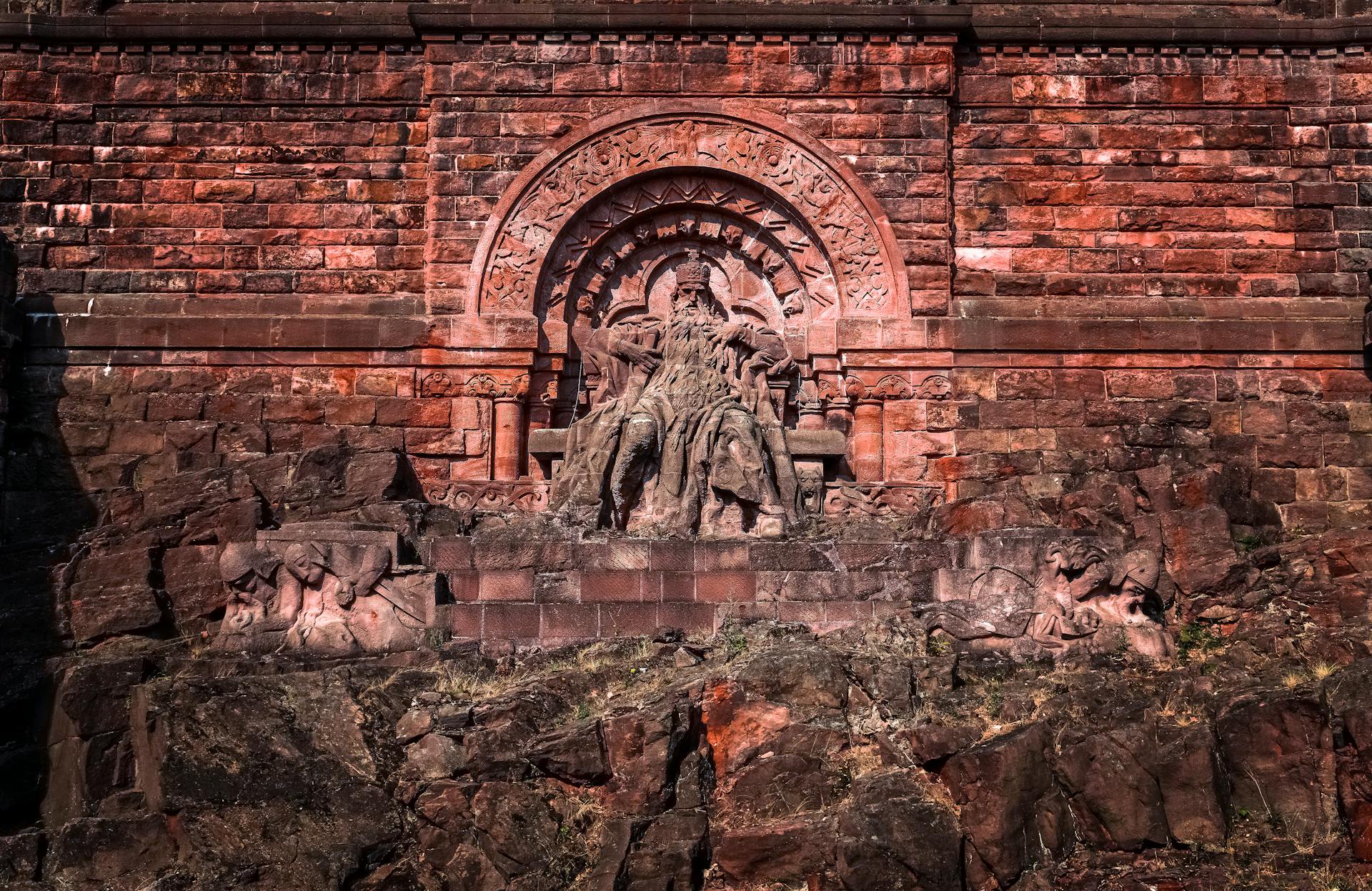 Stone monument of Frederick Barbarossa in a park setting, showcasing medieval German architecture.