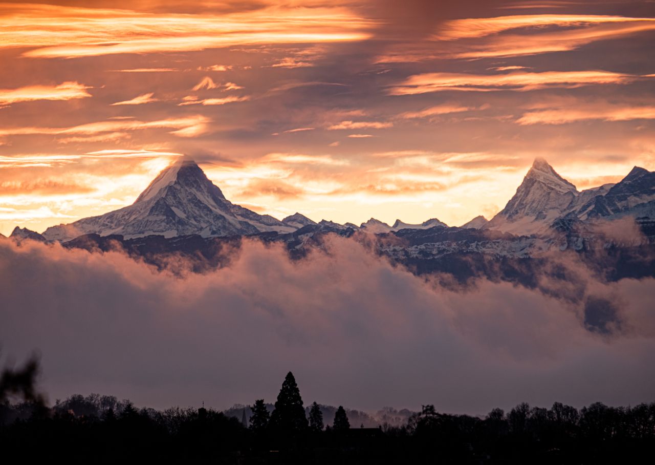 dramatic sunset view of snowcapped mountains with clouds and a scenic