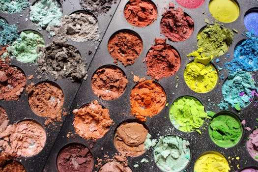 Close-up of a colorful eyeshadow palette with various shades and textures in a tray.