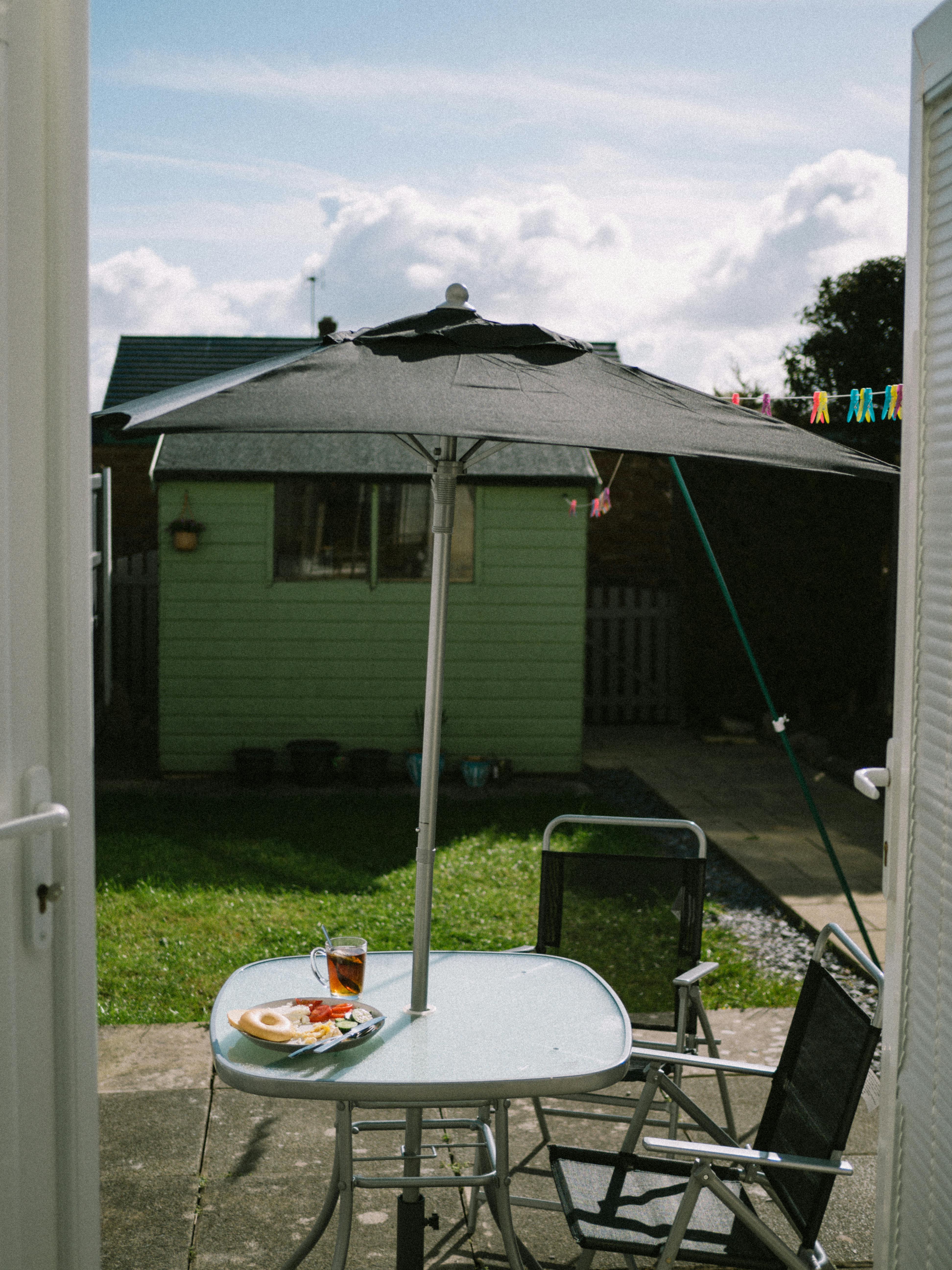 Sunny patio setting with chairs and table under umbrella, perfect for outdoor relaxation.