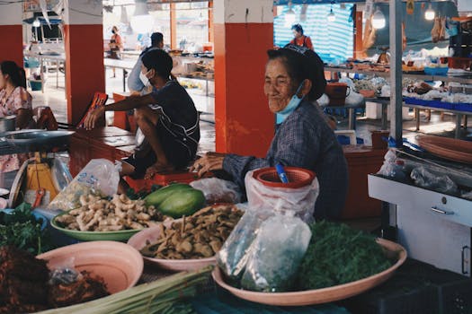 A bustling local market scene showcasing fresh produce and vendors engaging with customers in a communal setting.