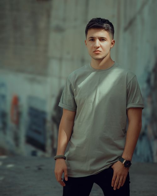 Free Stylish young man posing in a city street wearing casual clothing and a wristwatch. Stock Photo