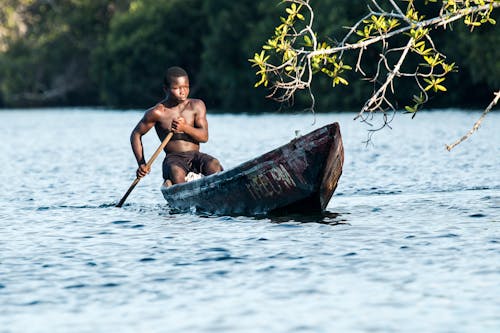 Man in Black Shorts Riding Rowboat during Daytime