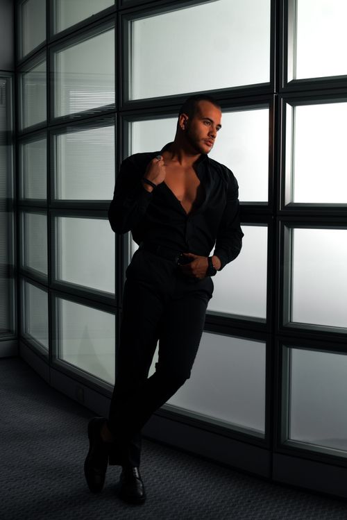 Free Sophisticated fashion photography featuring a man in a black outfit striking a pose indoors. Stock Photo