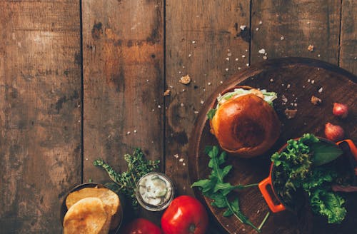 Free Burger and Vegetables Placed on Brown Wood Surface Stock Photo