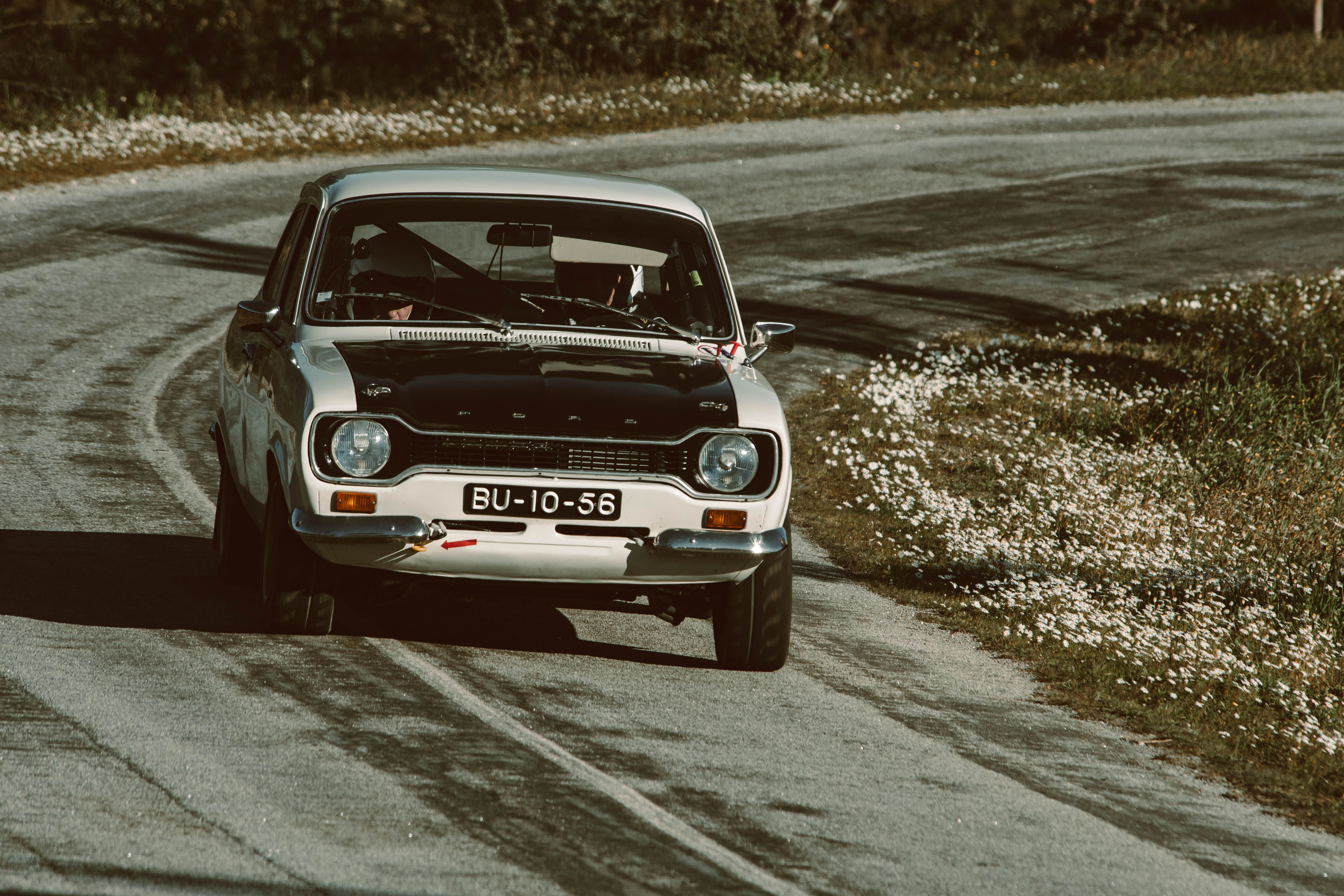 Classic white vintage car driving on a winding rural road, evoking nostalgia.