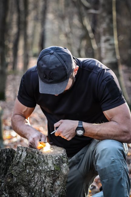 A man using a ferro rod with flint and steel technique to throw sparks and start a fire outdoors