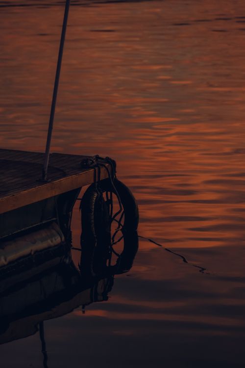Free A tranquil scene of a lake pier at twilight with warm reflections on the water. Stock Photo
