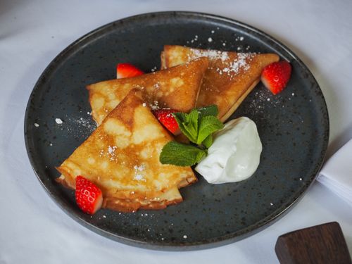 Free Delightful crepes served with fresh strawberries and whipped cream on a dark plate. Stock Photo