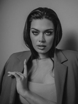 A captivating black and white portrait of a fashionable woman with striking eyes, exuding confidence.