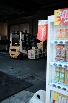 Indoor warehouse scene with forklift moving boxes near a vending machine.