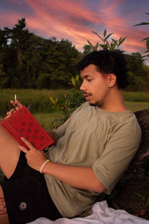 Man Sitting Outdoors at Sunset and Writing in a Journal 