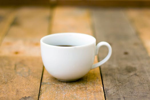 Simple white cup of coffee on rustic wooden table, perfect for a cozy morning