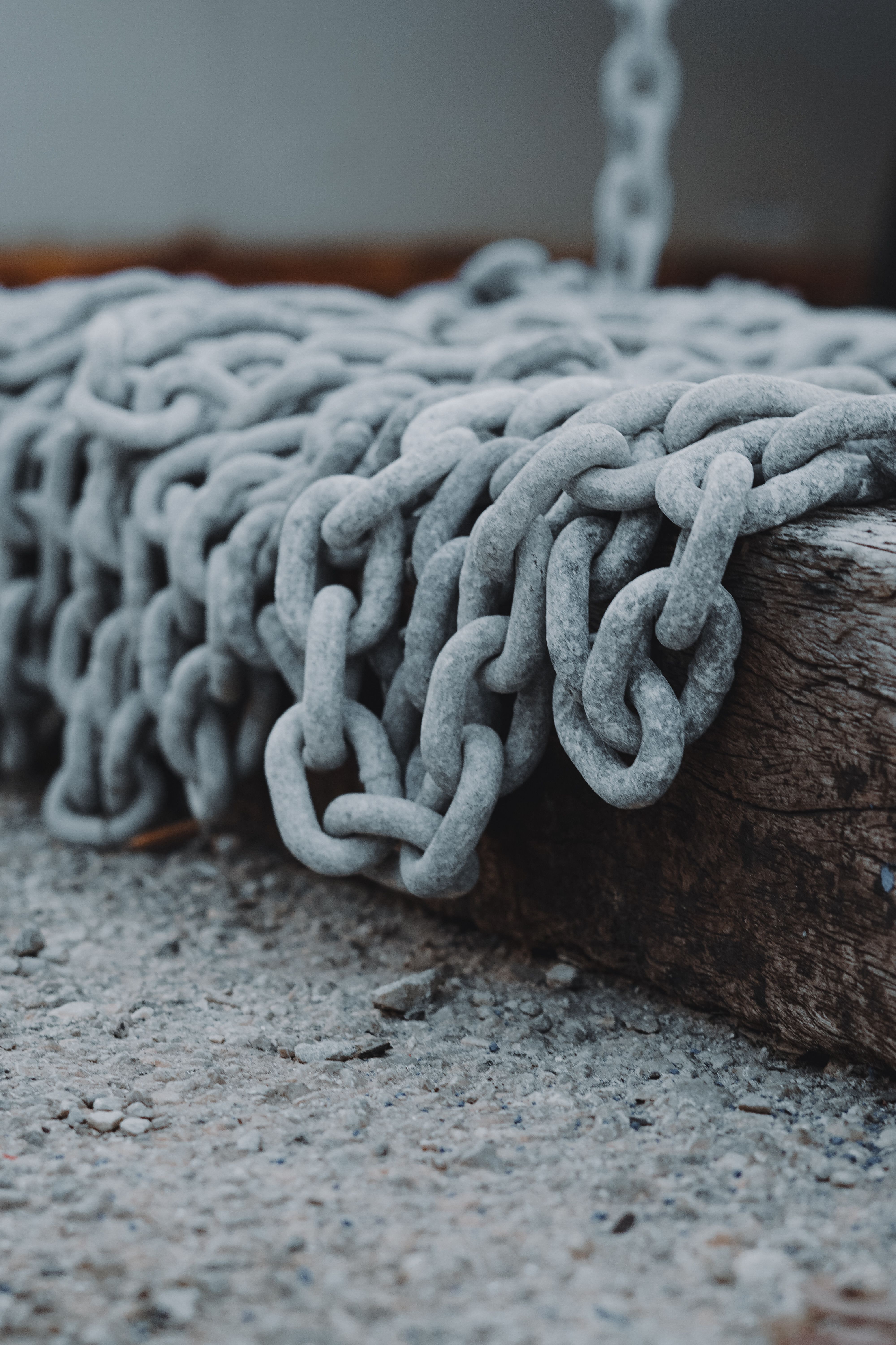 Close-up of thick metal chains on weathered wood, highlighting texture and pattern.