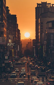 Vibrant city street at sunset with heavy traffic and skyscrapers in view.