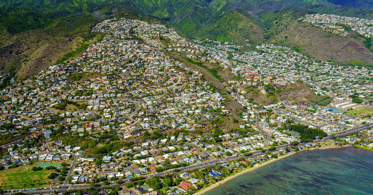High-angle shot of a coastal town nestled between hills and ocean waters.