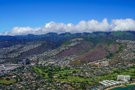 Photo by Cyrill Stunning aerial view of Honolulu showcasing vibrant green mountains under a clear blue sky.
