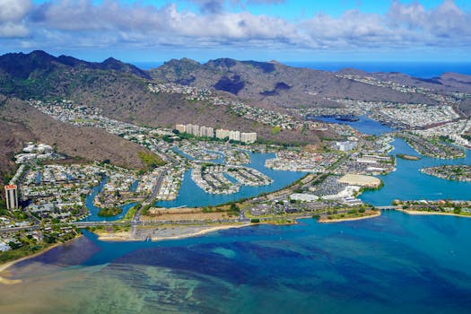 Stunning aerial view of a Hawaiian coastal cityscape featuring mountains, coastline, and the Pacific Ocean.