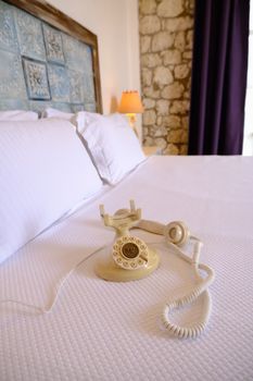 Retro rotary phone on bed adds nostalgic charm to cozy bedroom decor.