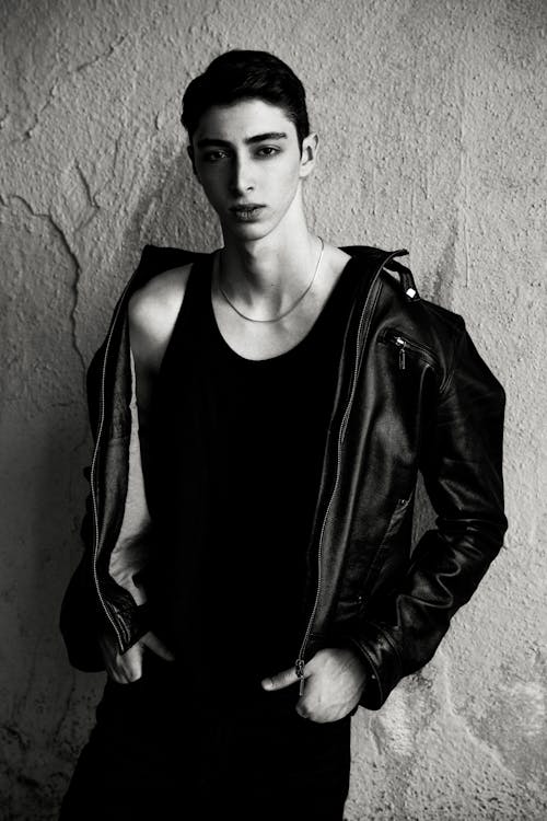 Black and White Photo of a Young Man in a Tank Top and Leather Jacket Standing with Hands in Pockets 