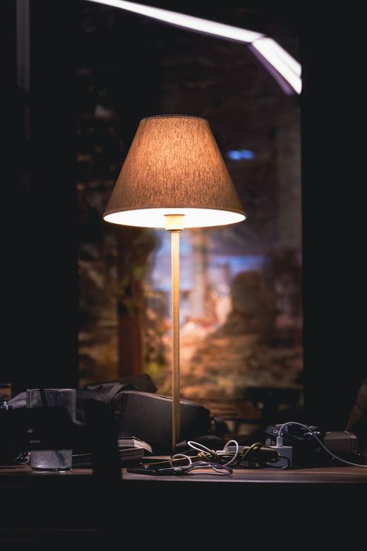 Warm desk lamp casting soft light across a dim workspace — Amine İspir on Pexels