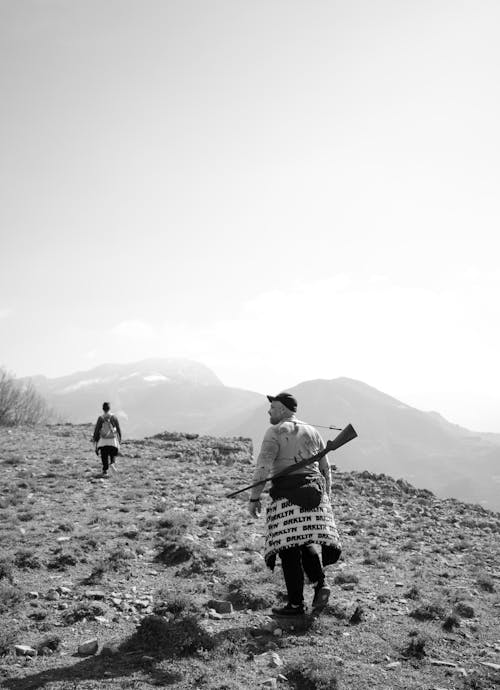 Woman and Man Carrying a Weapon Hiking in Mountains 